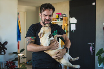 Man holding and playing with his french bulldog