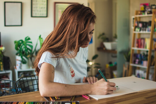 Red haired woman coloring a book