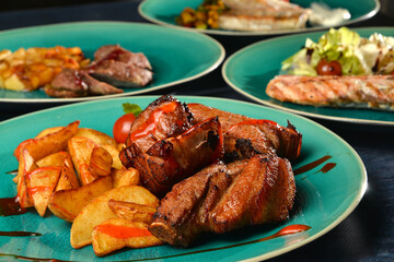 assorted fried fried meat and fish with garnish on plates closeup view place for text