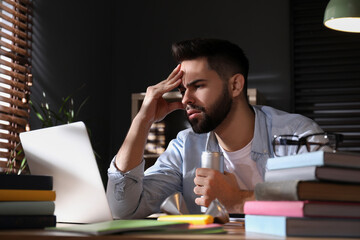 Tired young man with energy drink studying at home