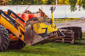 Excavator with raised up front bucket and vibration plate compactor