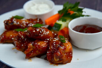 chicken bbq buffalo wings on white plate with sauce, closeup