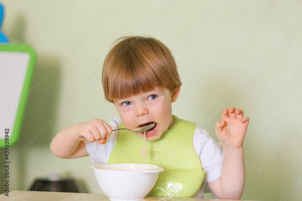 Wall mural happy cute infant baby boy spoon eats itself