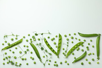 Green pea pods, seeds and twigs on white background