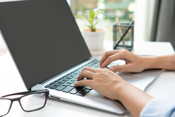 Asian woman freelancer is working on a new project on laptop computer with blank copy space screen for your advertising text message at home. Work from home, business and technology concept. Closeup