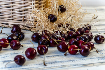 Cherry and cherry juice or wine on a wooden table, a decanter and a glass with juice, a basket with...