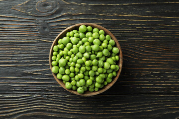 Bowl with pea seeds on wooden background