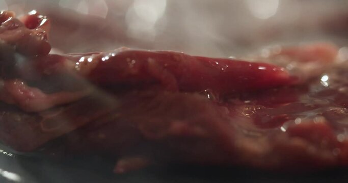 Cook plating meat steak on plate topping with salt, flowers and tomato creating a dish in a well appointed kitchen with an array of a equipment and appliances. Close up shot on 4k RED camera.