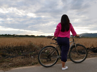 Fototapeta premium Woman Standing back with her bicycle looking nature