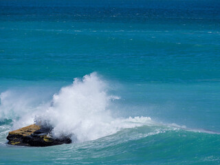 Waves crashing into a rock in the ocean in the Walker Bay Nature Reserve and Die Kelders (de Kelders). Overberg, Western Cape. South Africa