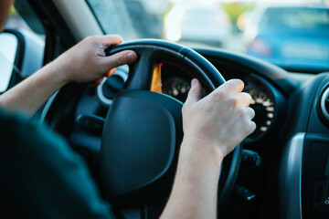Male hands close-up on the steering wheel of a car. Drive around the city and travel.
