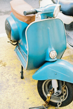 Blue vintage scooter parked in the street. 