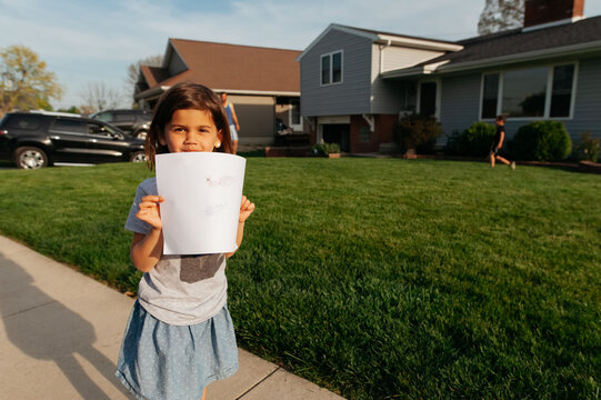 A happy girl holding up her artwork. 