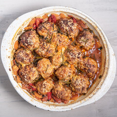 Meatballs in sauce baked with cheese in an enamel pan, top view
