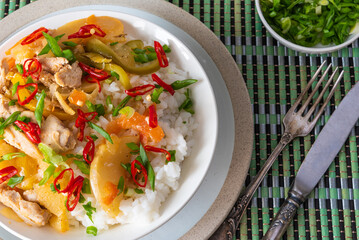 Pork with pepper and pineapple with rice in a plate, close-up, top view - a traditional dish of the Caribbean cuisine