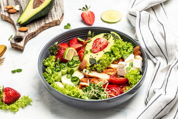 Ketogenic diet. chicken salad with avocado, feta cheese, quail eggs, strawberries, nuts and lettuce on white background. Keto paleo breakfast. Delicious balanced food concept