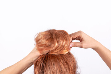 Naklejka premium The red-haired girl makes a careless beautiful bun hairstyle.