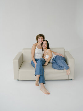 Middle age woman with short hairstyle and Young dwarf woman sitting on sofa
