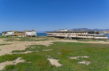 Fototapeta premium An old abandoned river boat stands on the ground near the sea.