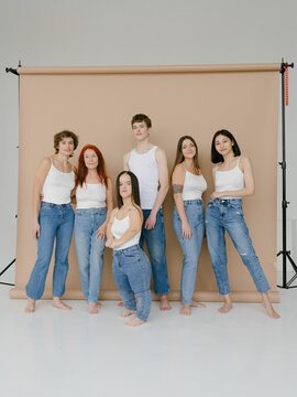 Group portrait of diverse people in similar outfits in studio beige background