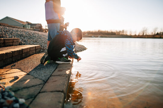 A child throwing a rock into the water. 