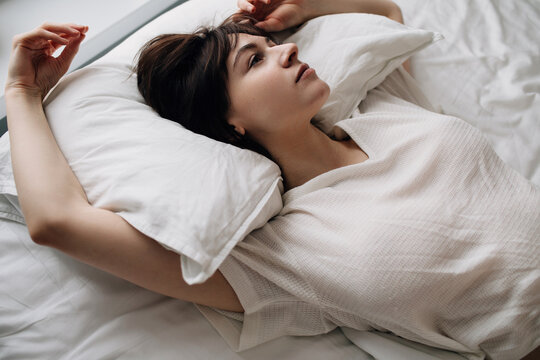 Pensive Woman lying in bed in morning
