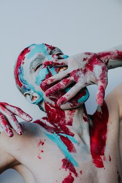 Crazy man with body art biting hand
