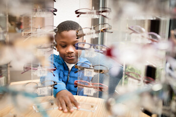 Black boy looks at display of glasses