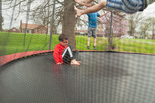 Boy being bounced on a trampoline by father. 