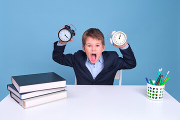 Alarm clocks in the hands of a screaming boy in primary school, copy space