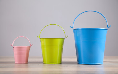 Pink, blue, green bucket on the desk.