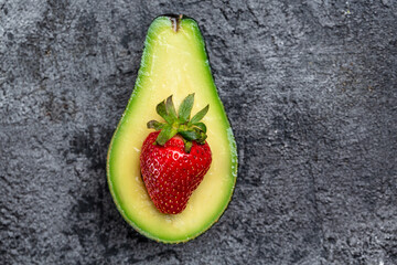Avocado cut half and slice with strawberry on dark background. Detox concept. Long banner format. top view