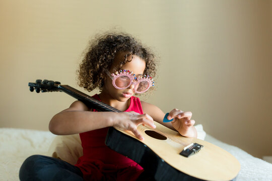 Cute girl in novelty glasses picks at guitar