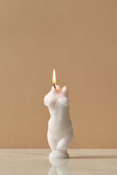 Candle with female shape on brown background