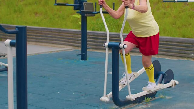 Senior woman grandmother 70 years old doing sport training exercising workout on orbitrek playground. Active elderly old pensioner cardio morning aerobics routine. Fitness leisure. Healthy lifestyle