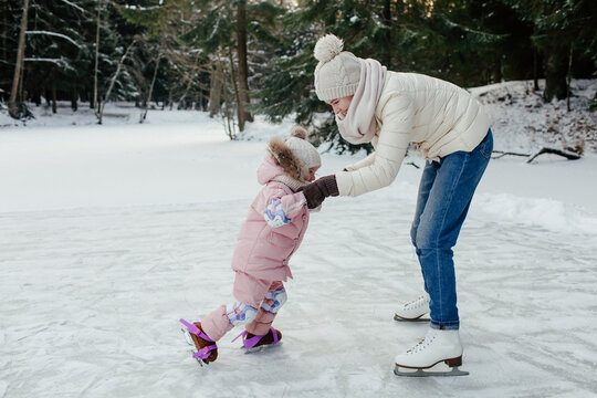 Mother and little kid learning skating on ice
