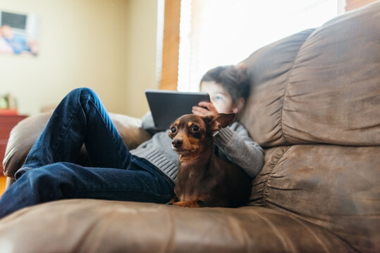 Girl and dog resting on the couch together. 