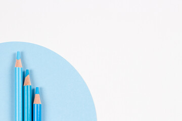 Light blue colored pencils on geometric blue and white background. Minimalistic geometric lines,...