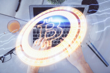 Double exposure of man's hands typing over computer keyboard and crypto currency theme hologram...