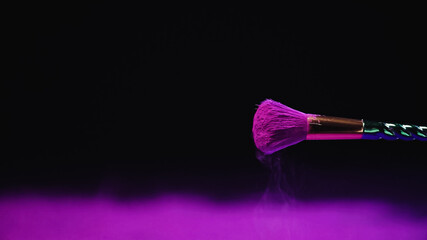 soft cosmetic brush with vibrant purple powder near dust on black