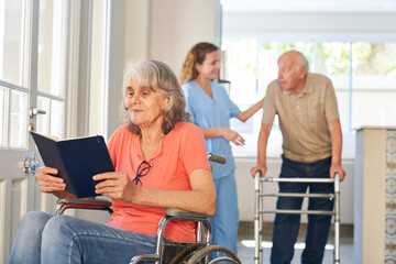 Senior Patientin im Rollstuhl liest ein Buch im Seniorenheim