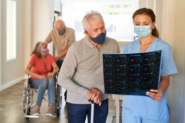 Ärztin und ein Senior schauen gemeinsam auf MRT Aufnahme