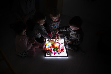 Children playing with a light board in the dark