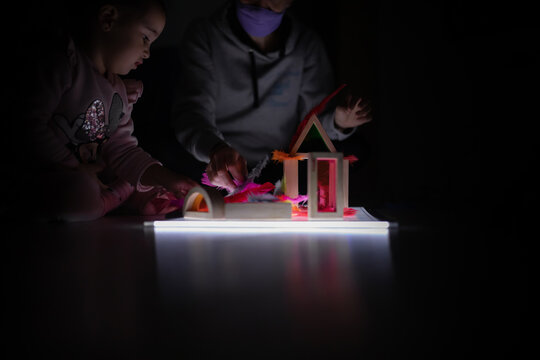 Children playing with a light board in the dark