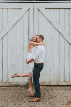 Groom Picking up Happy Bride in front of Barn