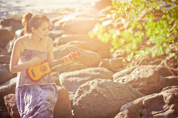 Woman playing ukulele on sunlight beach-Filtered Images‏