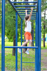 Obraz premium A little girl of preschool age plays on a projectile on the playground.