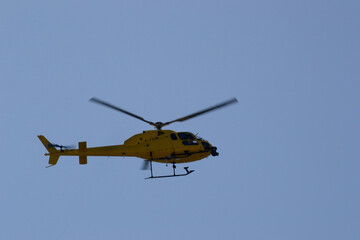 Yellow helicopter flying in the deep blue sky