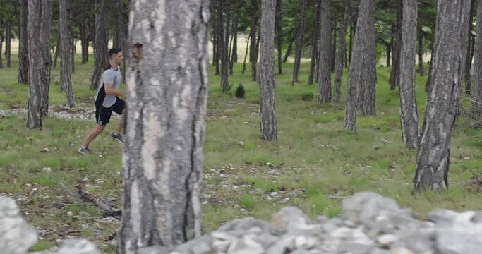 Male athlete running through the forest. An active young man having an intense jogging workout.
