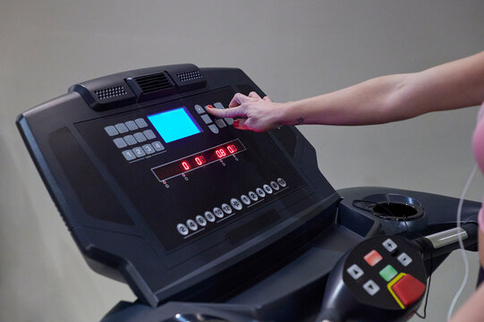 Woman adjusting settings on a running machine